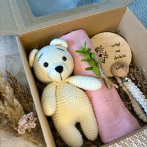 zestaw prezentowy dla noworodka z misiem, zawieszką do smoczka oraz pieluszką muślinową.